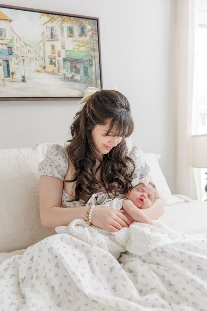 Mother holding her newborn baby near a window during an in-home session in Boise
