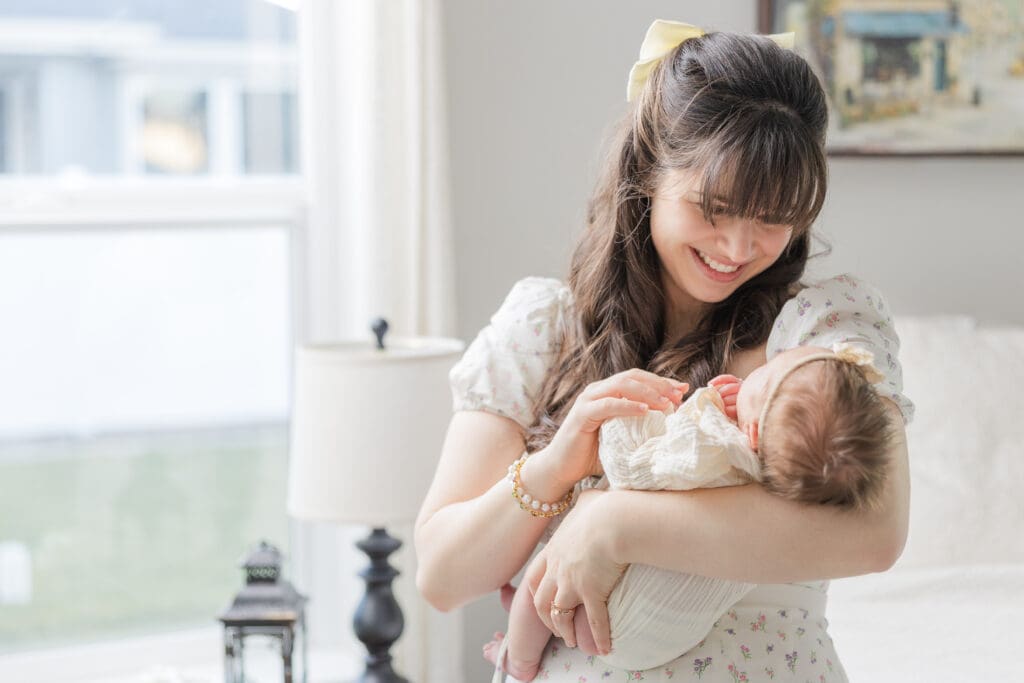 Mother smiling down at newborn during a Boise in-home session