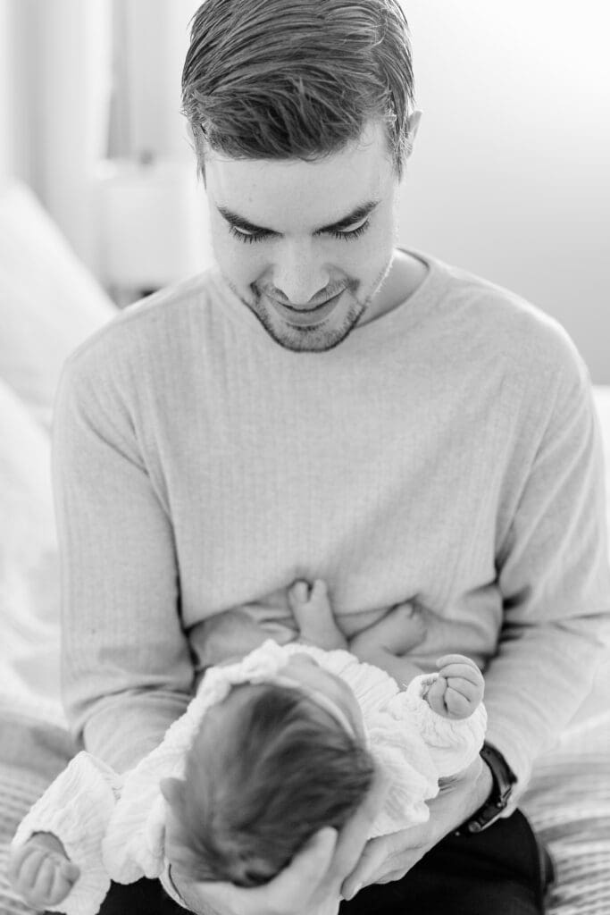 Black and white image of dad looking down at his newborn baby in ID