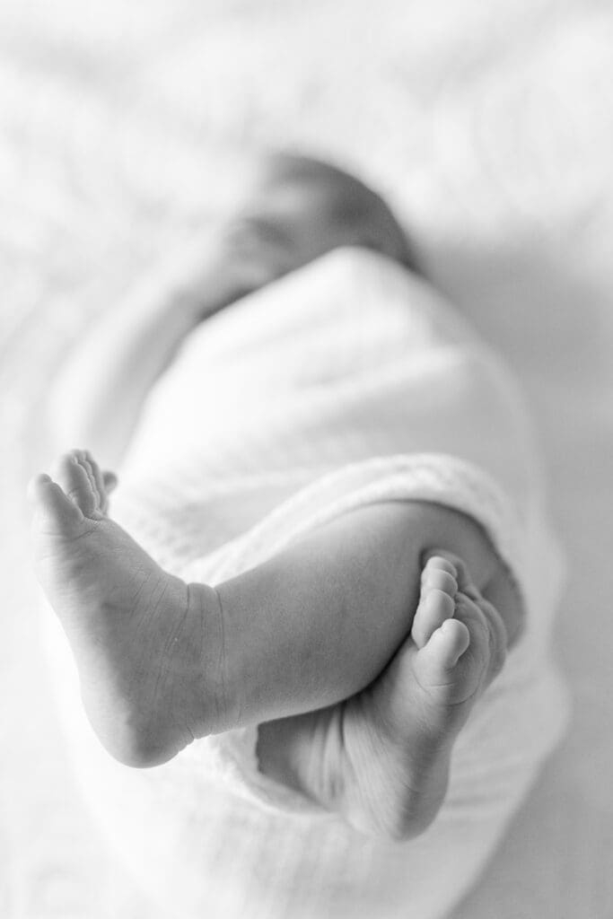 Black and white close-up of newborn feet during in-home session