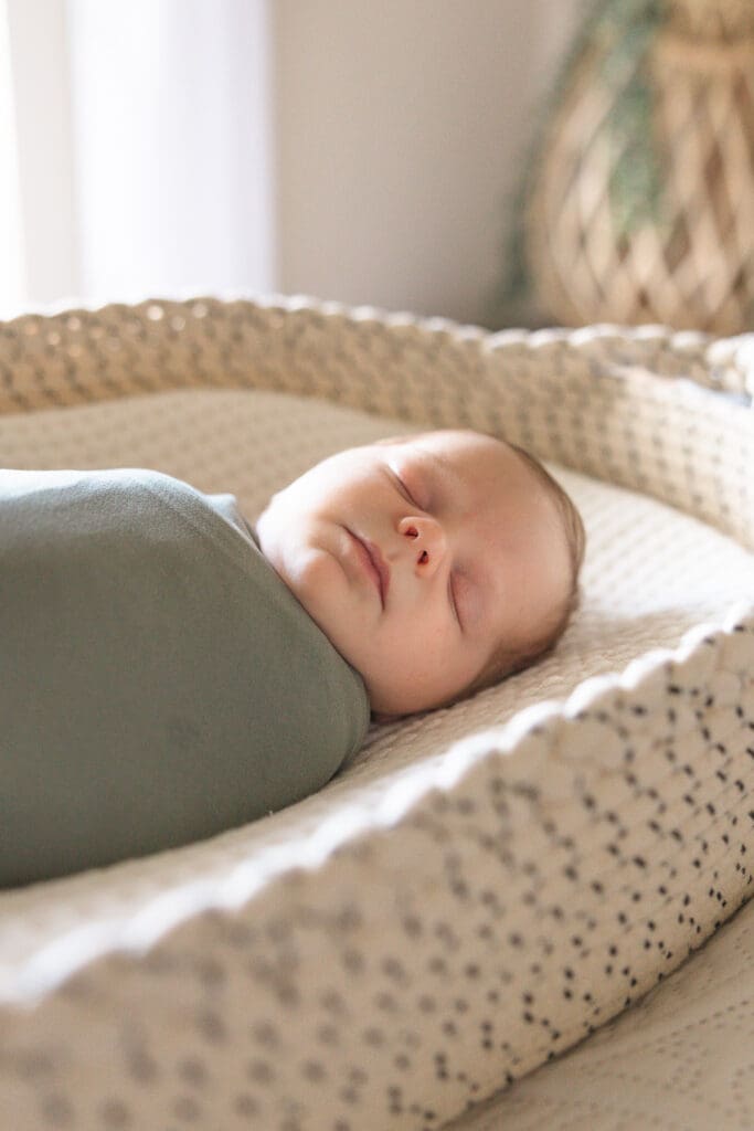 Newborn baby sleeping in woven bassinet during in-home session