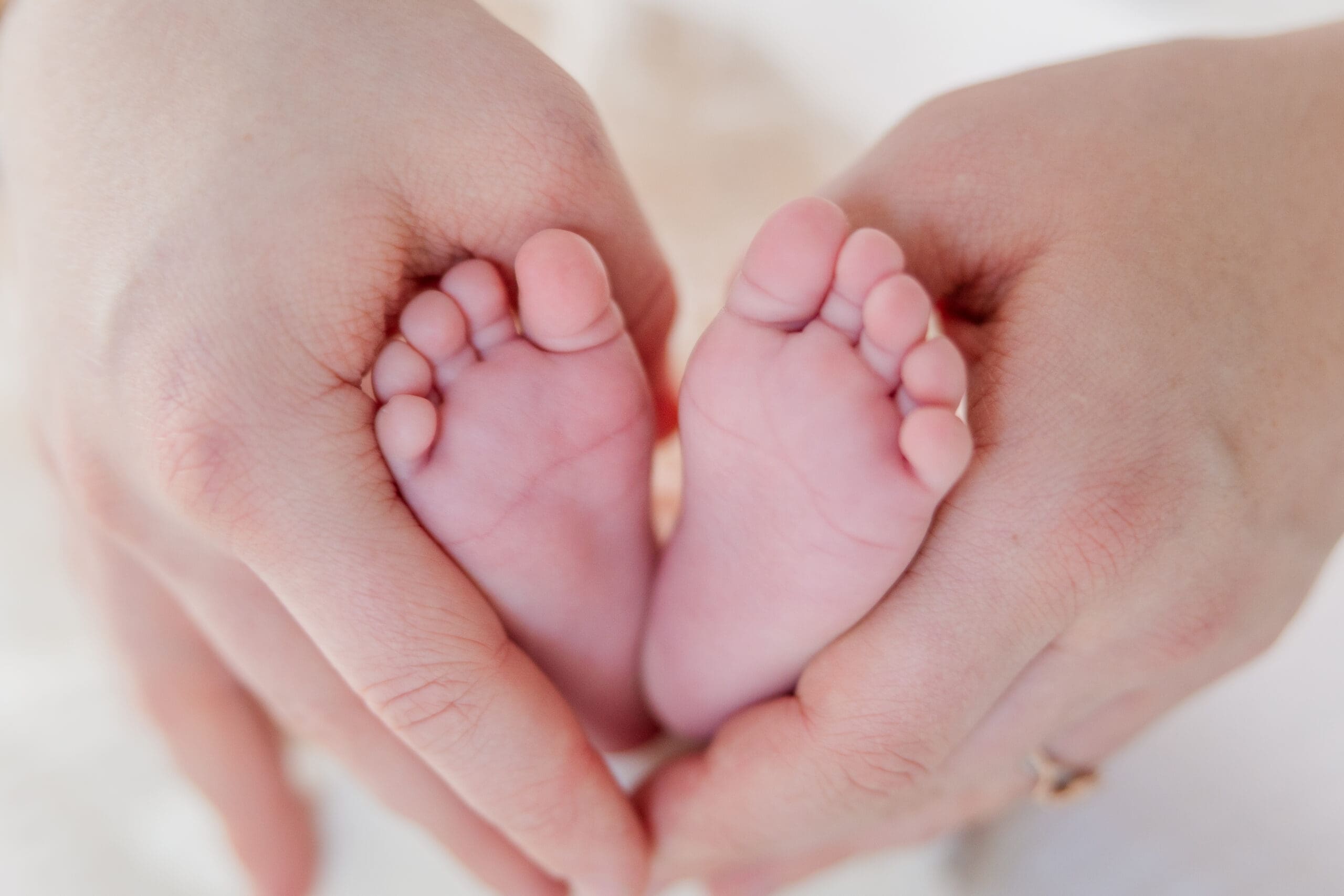 Close-up of newborn feet resting in parents’ hands during in-home session