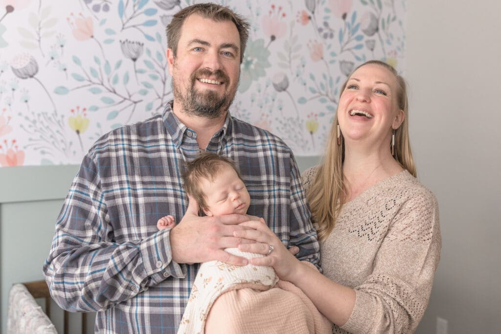 Parents smiling while holding their sleeping newborn