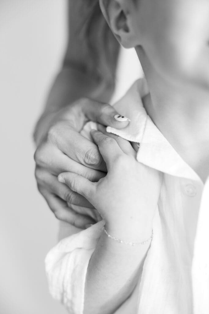 Black and white detail photo of young boy holding his mother’s hand