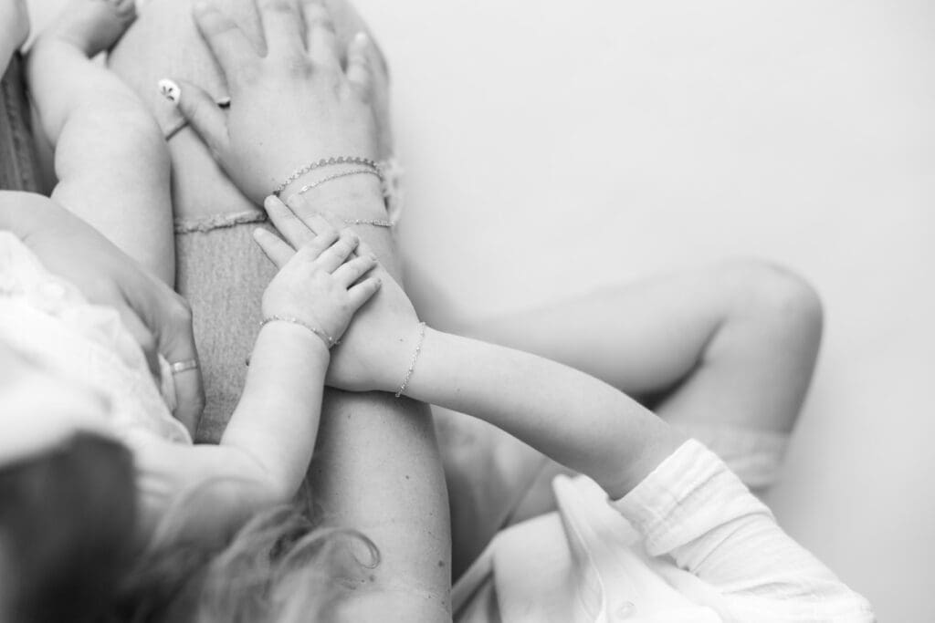 Lifestyle family photography detail of sibling hands and mother’s arm