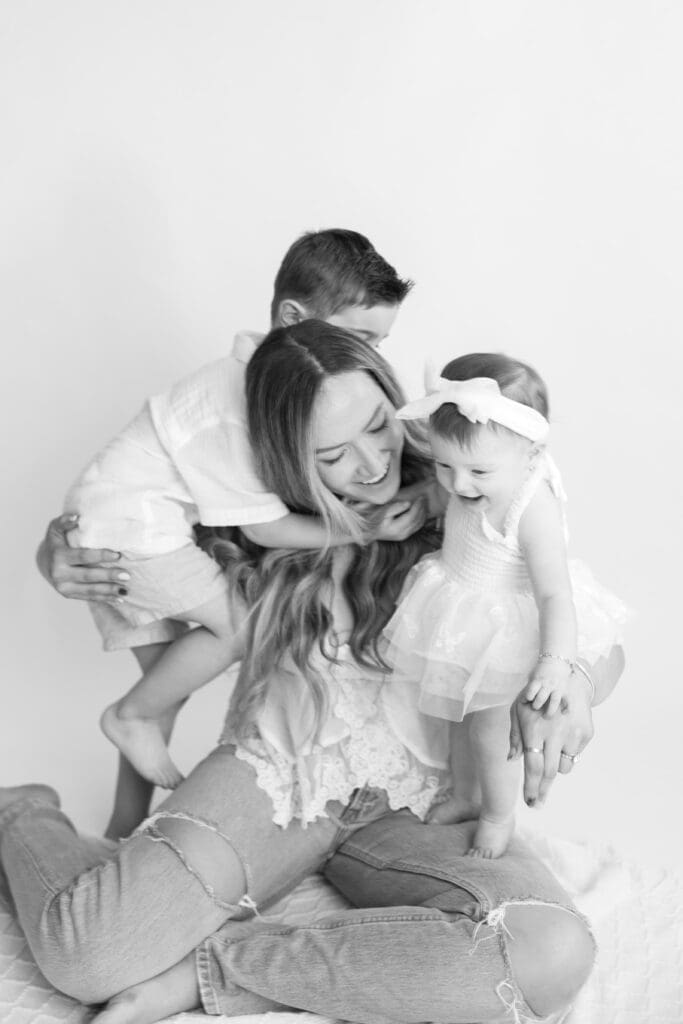 Black and white family portrait with mother holding both children close