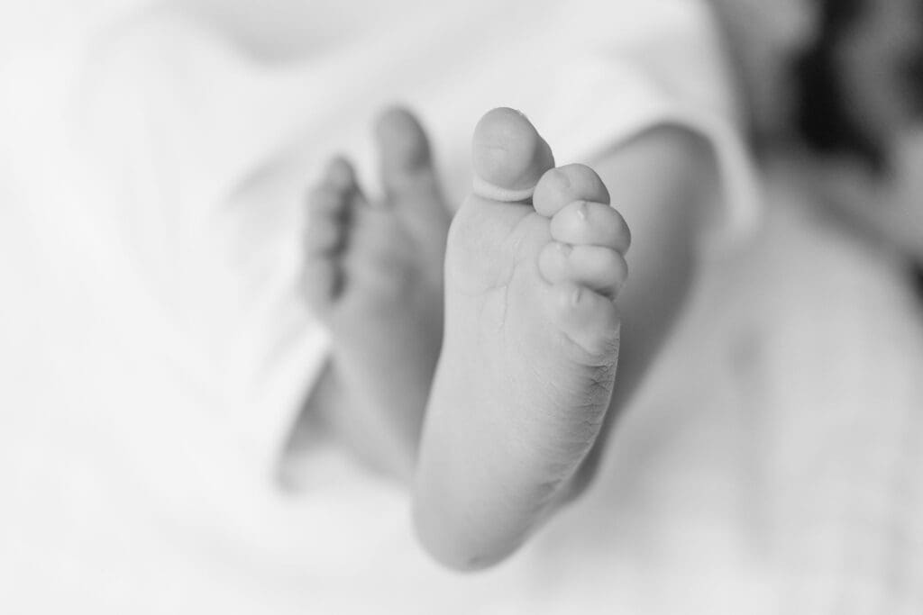 Black and white detail photo of tiny newborn feet during baby session