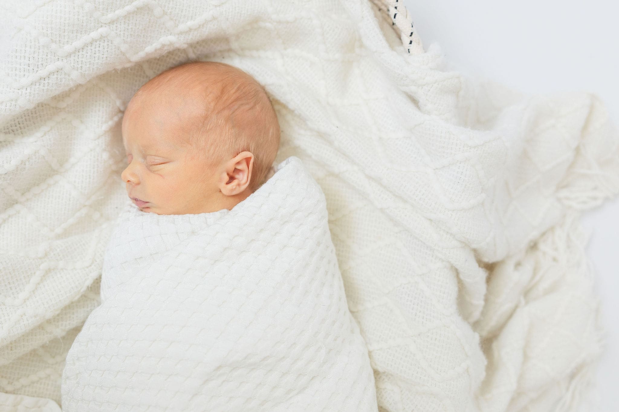 Emmett newborn photographer image of swaddled newborn on white bedding