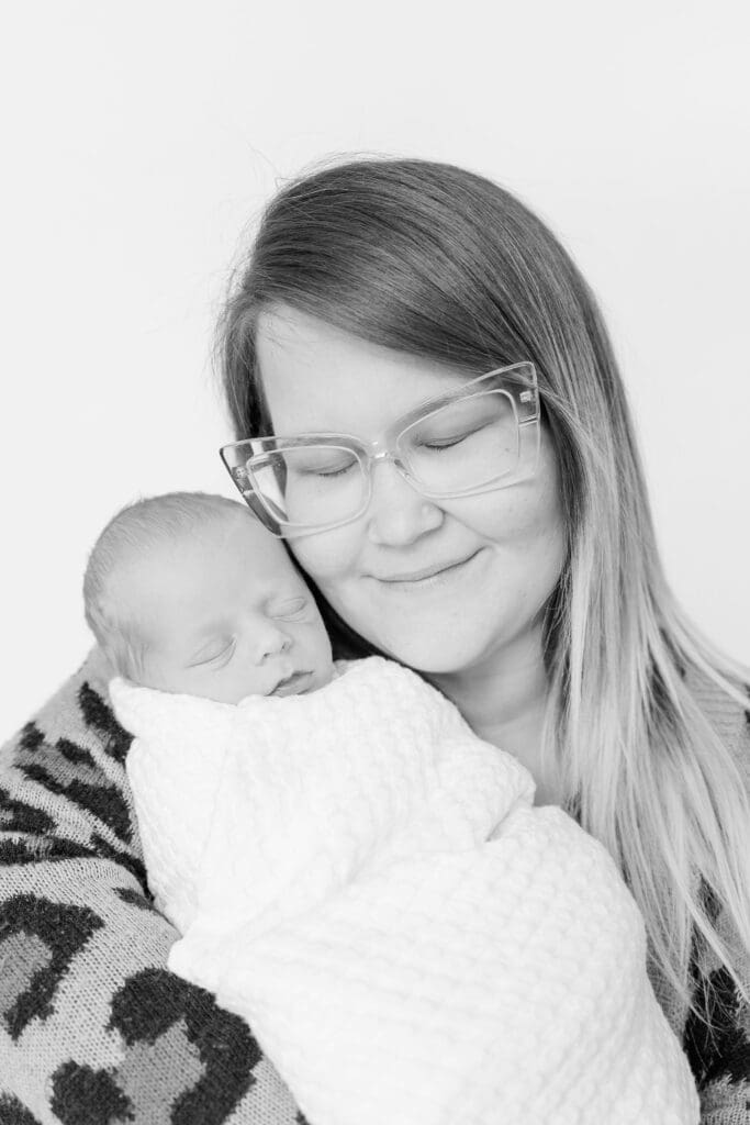 Mom cuddling swaddled newborn baby during studio newborn session
