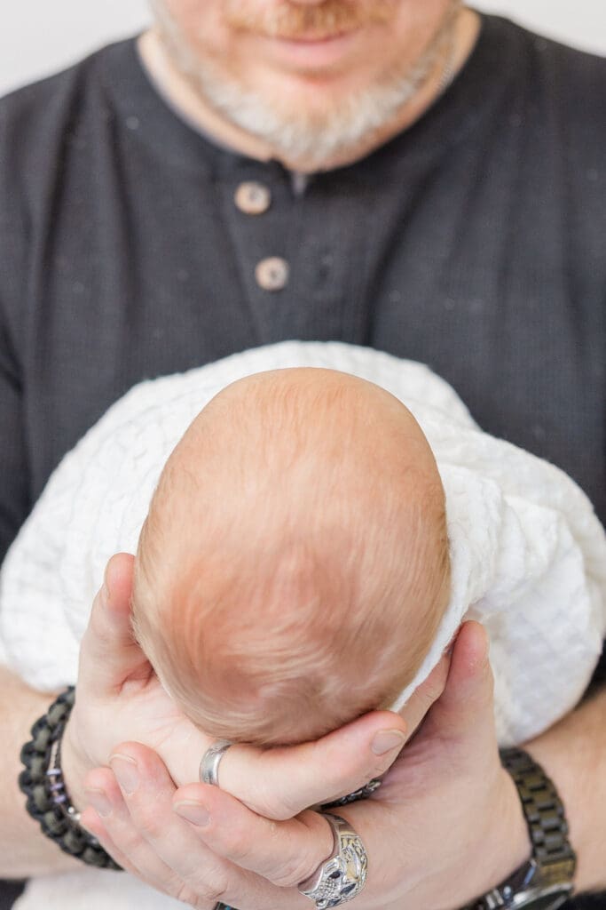 Emmett newborn photographer close-up newborn portrait with father’s hands