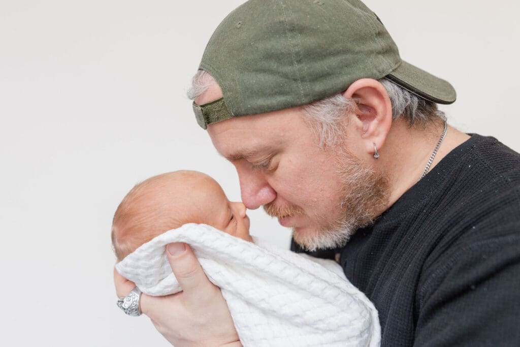 Dad holding newborn close during soft studio newborn photography session