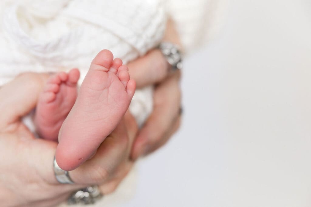 Tiny newborn feet resting in parent’s hands during studio session