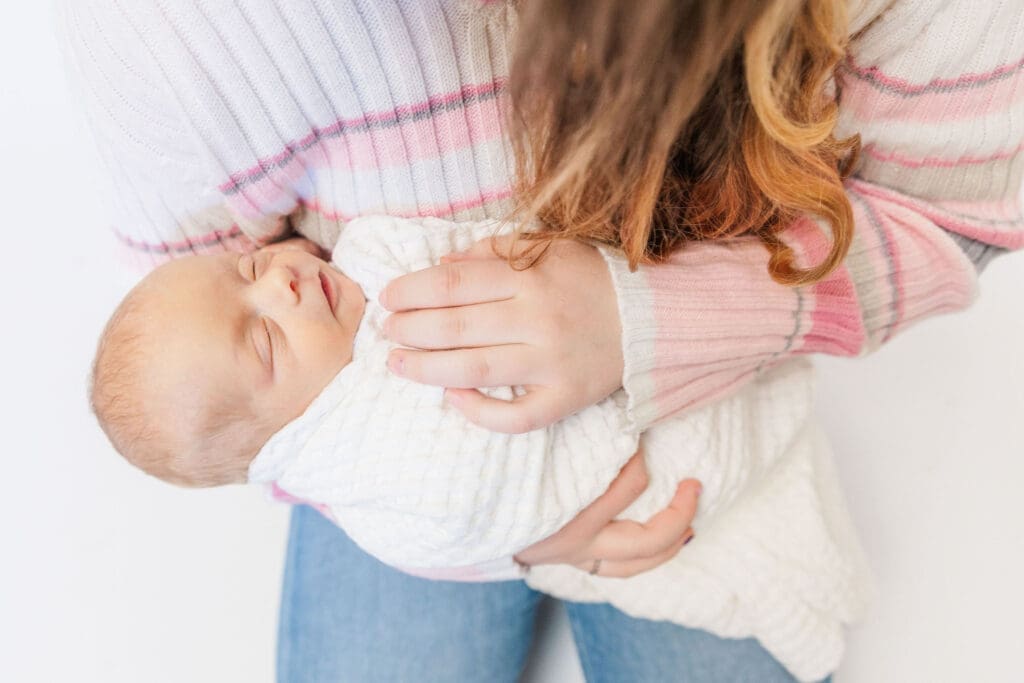 Older sibling cuddling newborn baby during studio family session