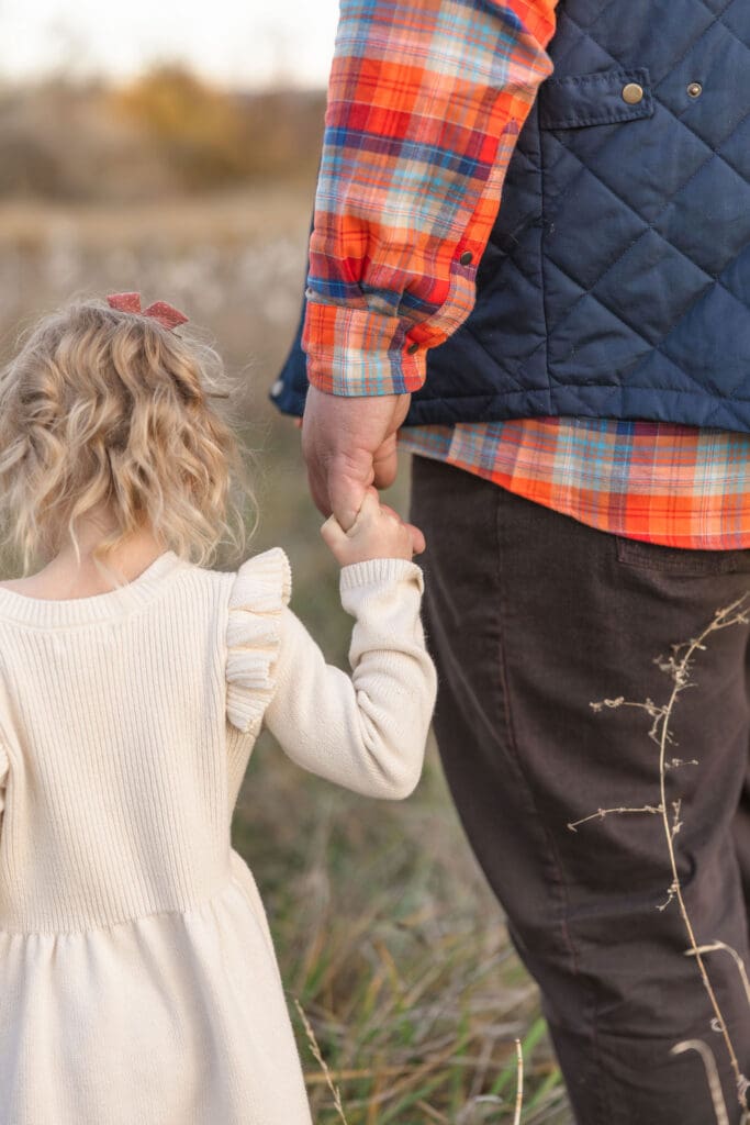 Close-up of a daughter holding her father's hand during an outdoor family session